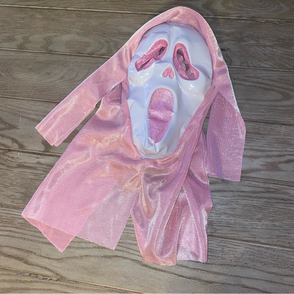 Pink glitter Halloween mask dented on white plastic as pictured